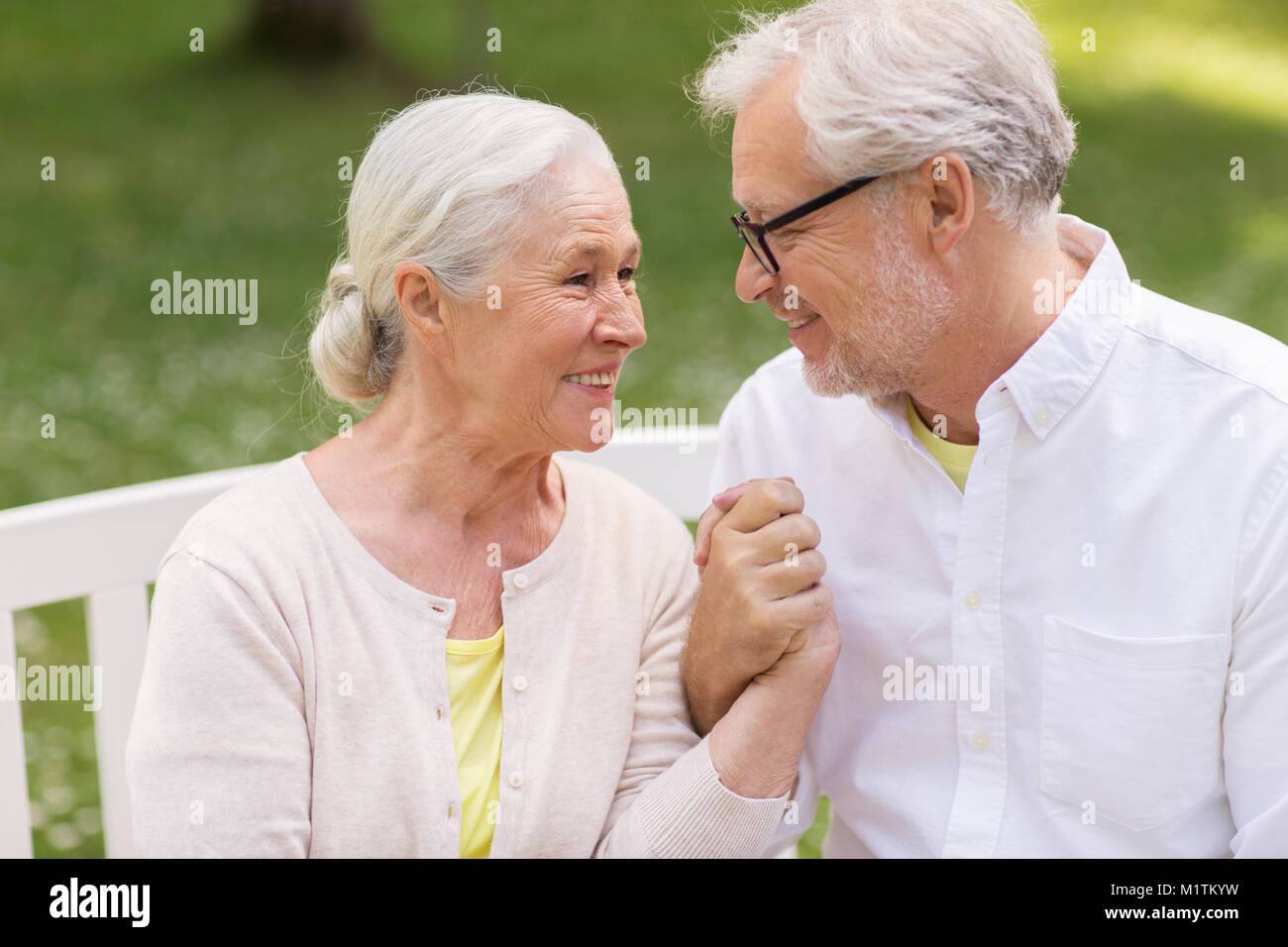 happy senior couple sitting on bench at park Stock Photo - Alamy