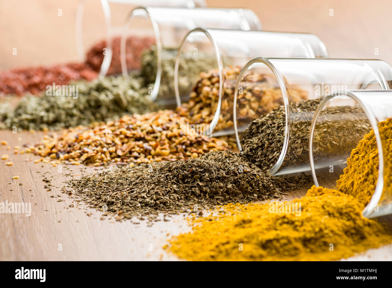 glass jars with various spices on wooden table, closeup on oregano. Stock Photo