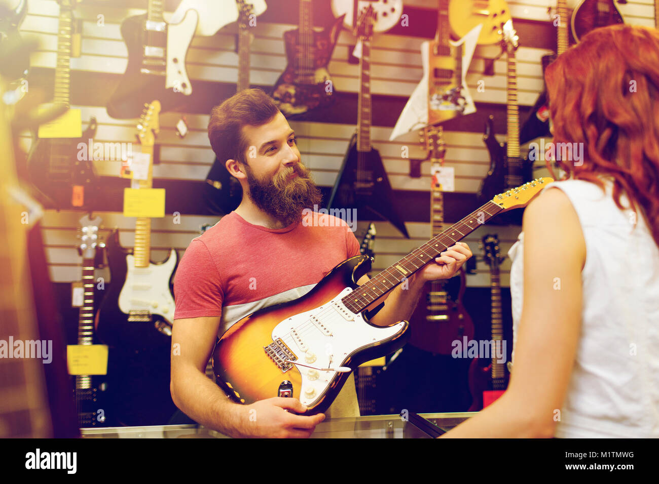 assistant showing customer guitar at music store Stock Photo Alamy