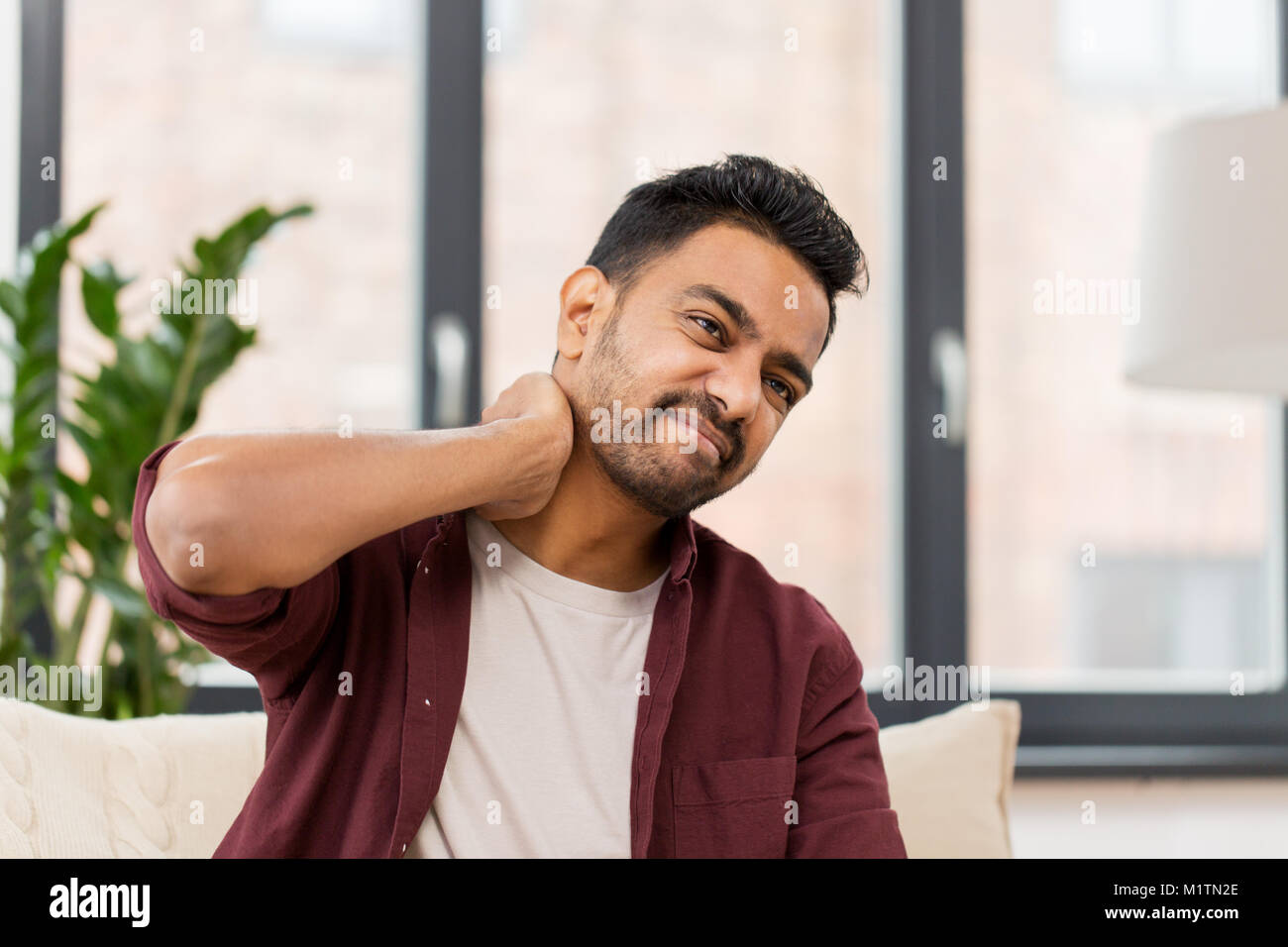 unhappy man suffering from neck pain at home Stock Photo - Alamy