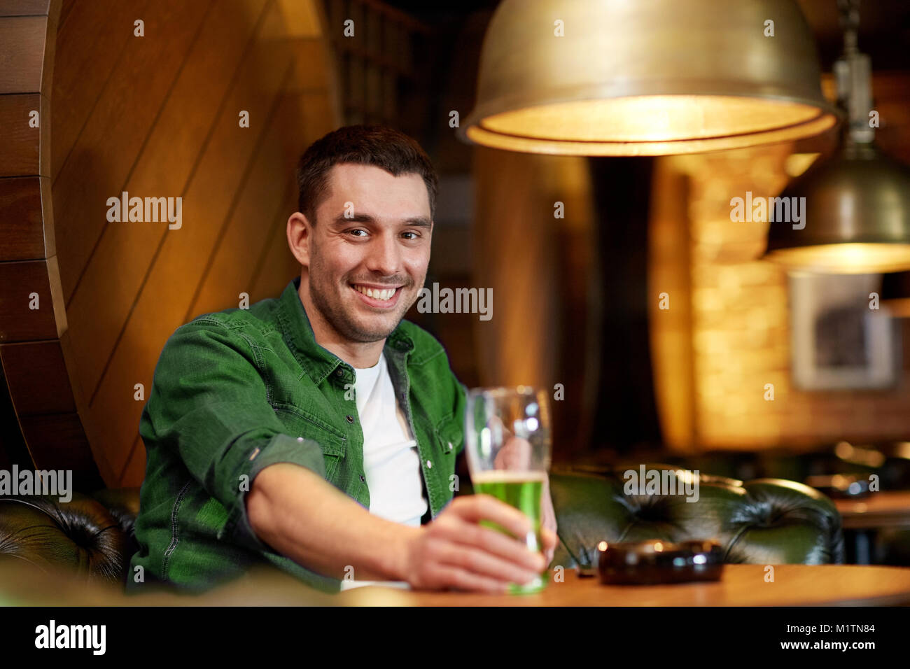man drinking green beer at bar or pub Stock Photo