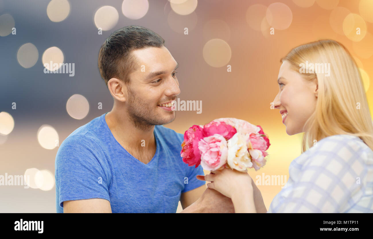 happy couple with flowers over lights background Stock Photo - Alamy