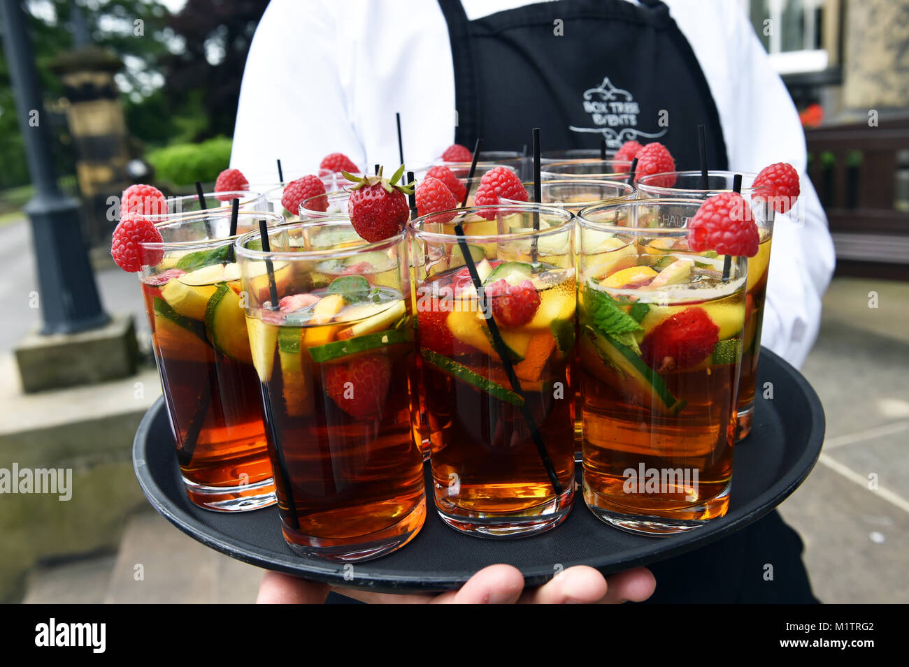 waiter carries tray of Pimms drinks filled with fruit UK Stock Photo