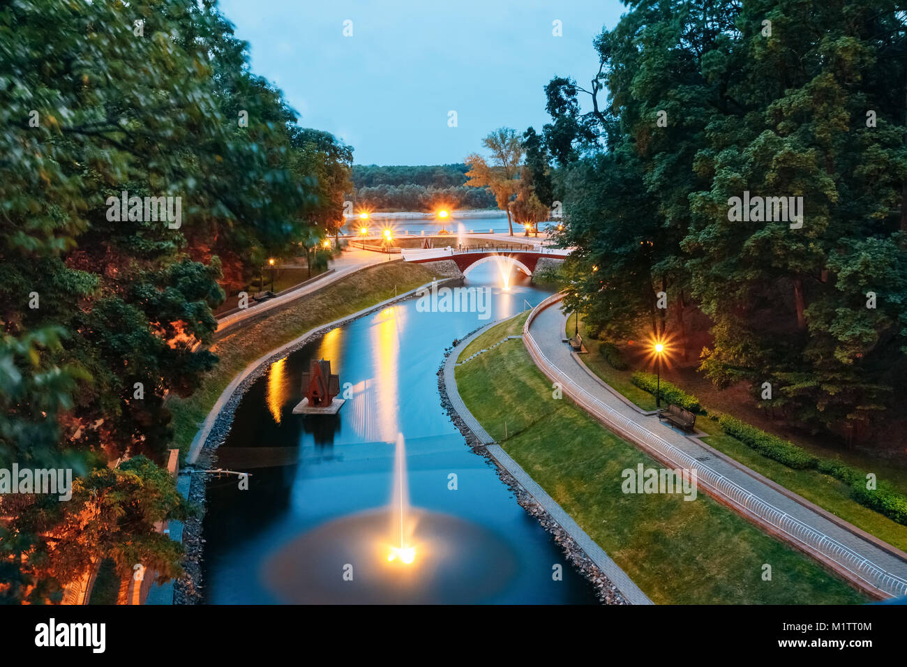 Water canal in the city park with the lights and night illumination over a stone bridge leading to the river Sozh Stock Photo