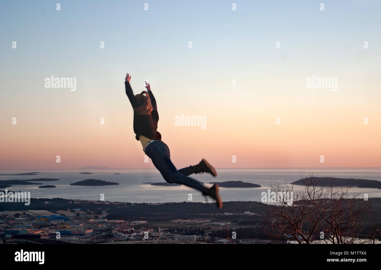 girl jumping on a hill with a view of the city and sea Stock Photo
