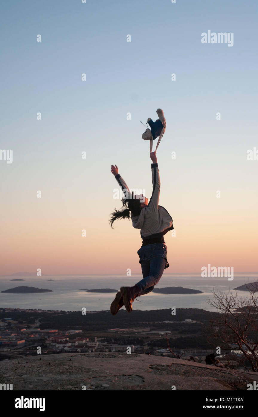 girl jumping on the hill reaching the sky Stock Photo