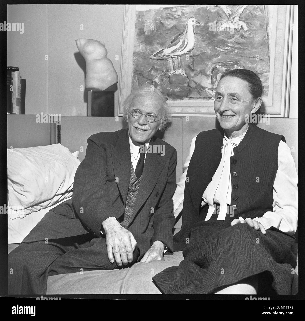 Photographer Alfred Stieglitz and artist Georgia O’Keeffe in New York City. The married couple are at 'An American Place' for an exhibition of John Marin in 1942. Artwork on wall is “Sea and Gulls” by Marin. Stock Photo