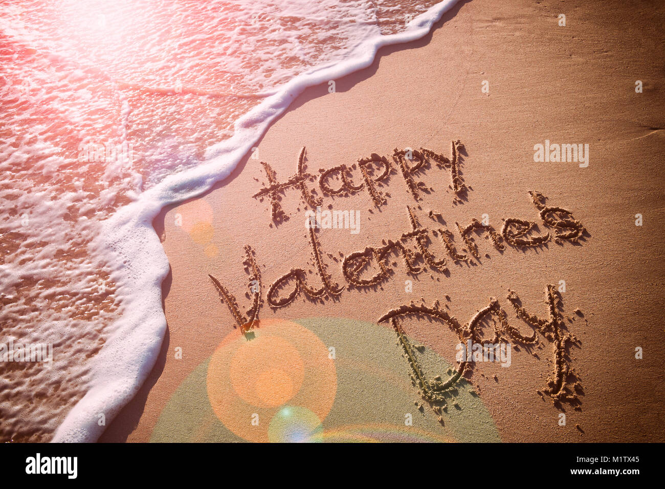 Happy Valentine's Day message handwritten on smooth sand beach Stock