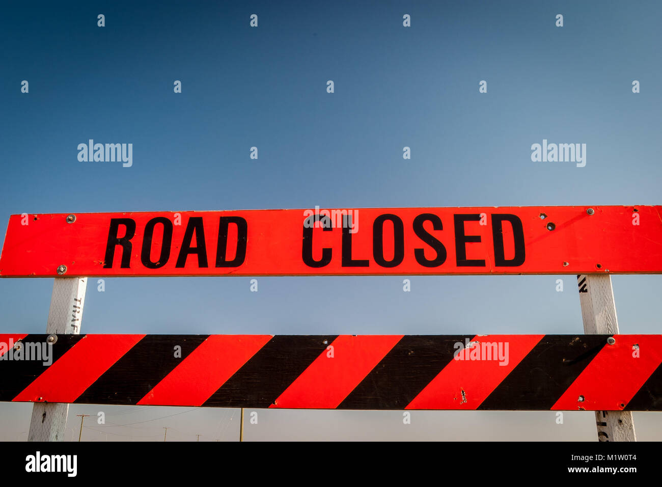 A Road Closed construction sign against a clear blue sky background