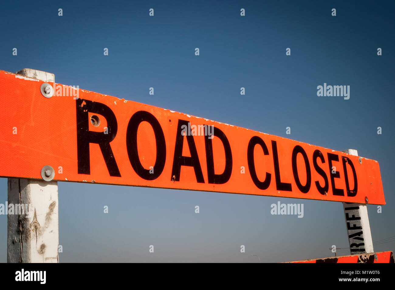 A Road Closed construction sign against a clear blue sky background