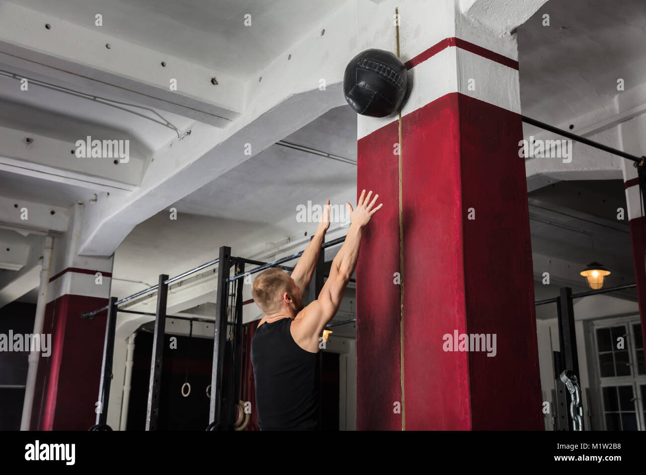 Young Male Athlete Doing Wall Balls Exercise At The Gym Stock Photo