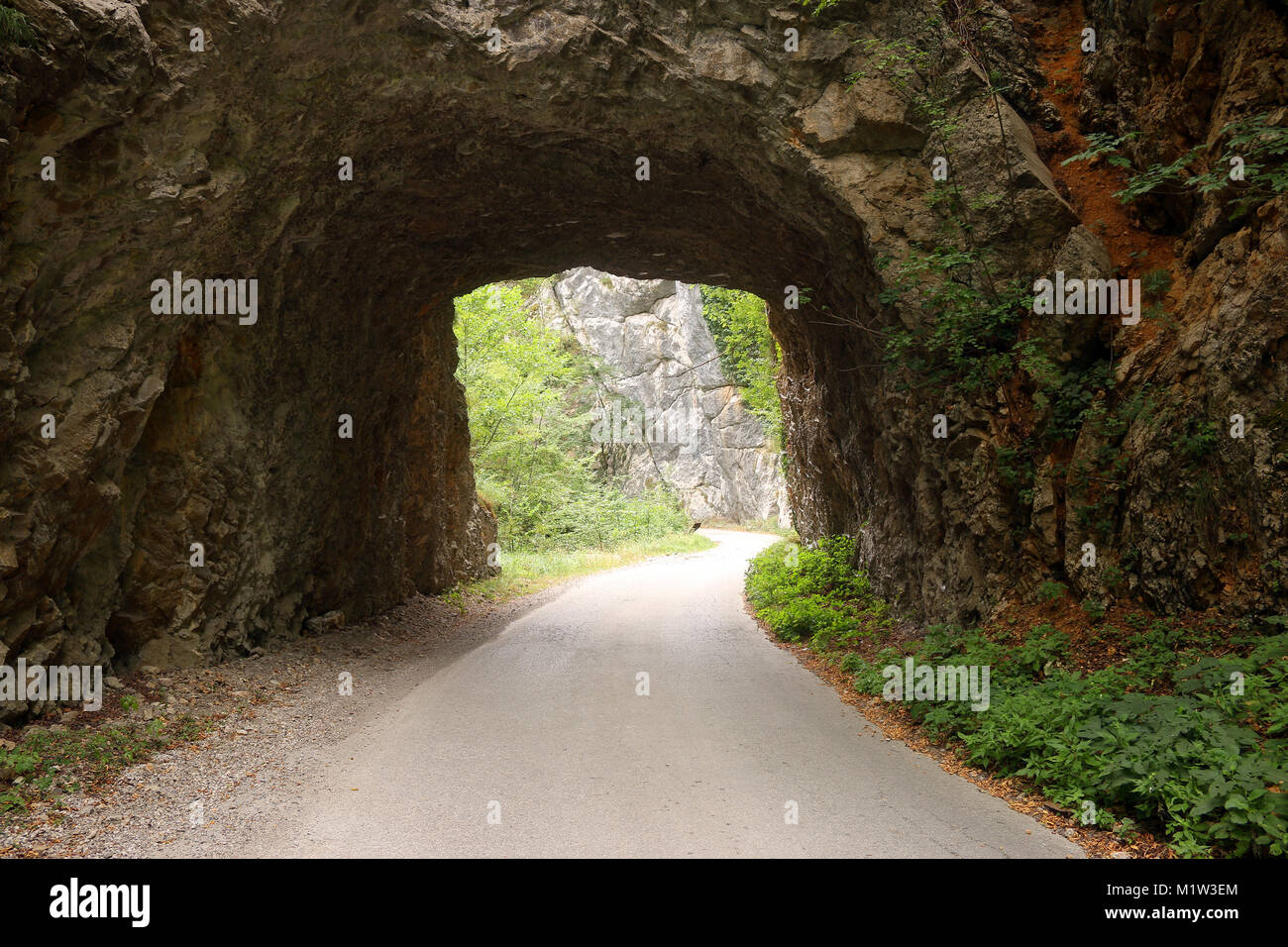 the mountain road passes through a stone tunnel Stock Photo