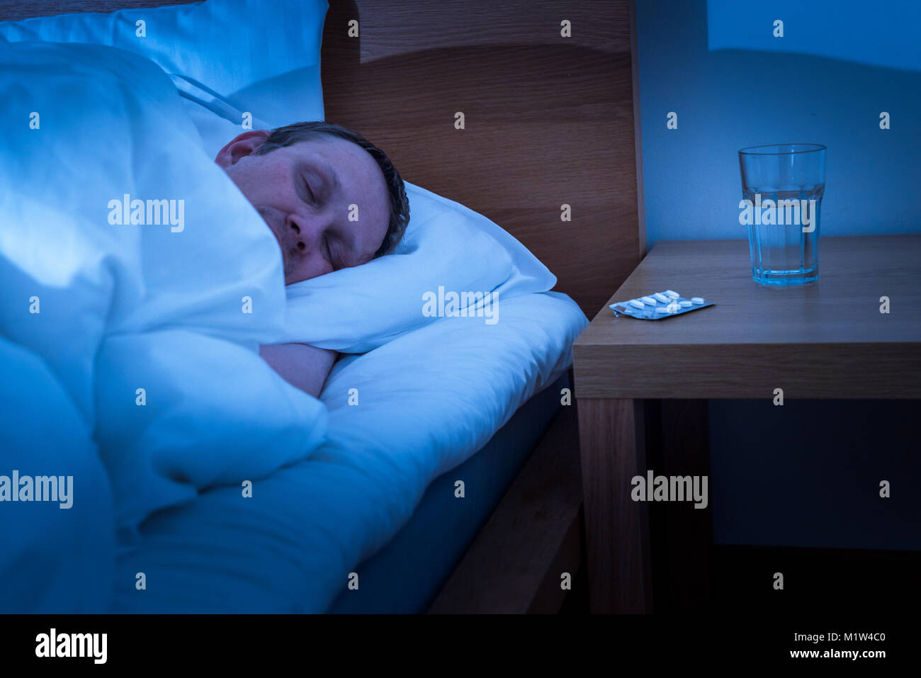 Man trying to sleep in bed with sleeping pill Stock Photo