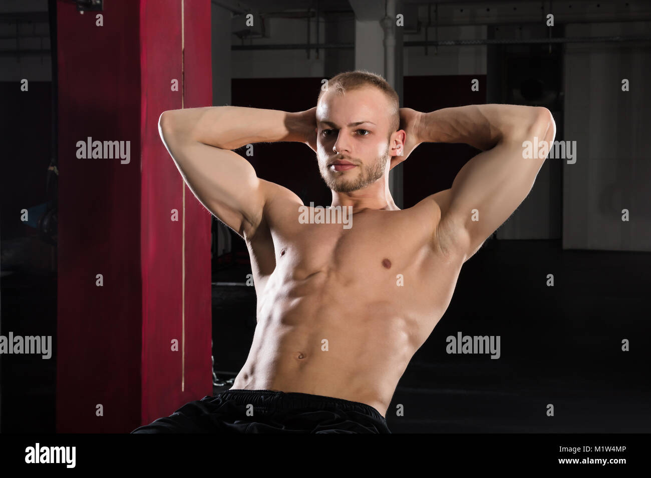 Portrait Of A Young Athlete Man Doing Stretching Exercise In The Gym ...