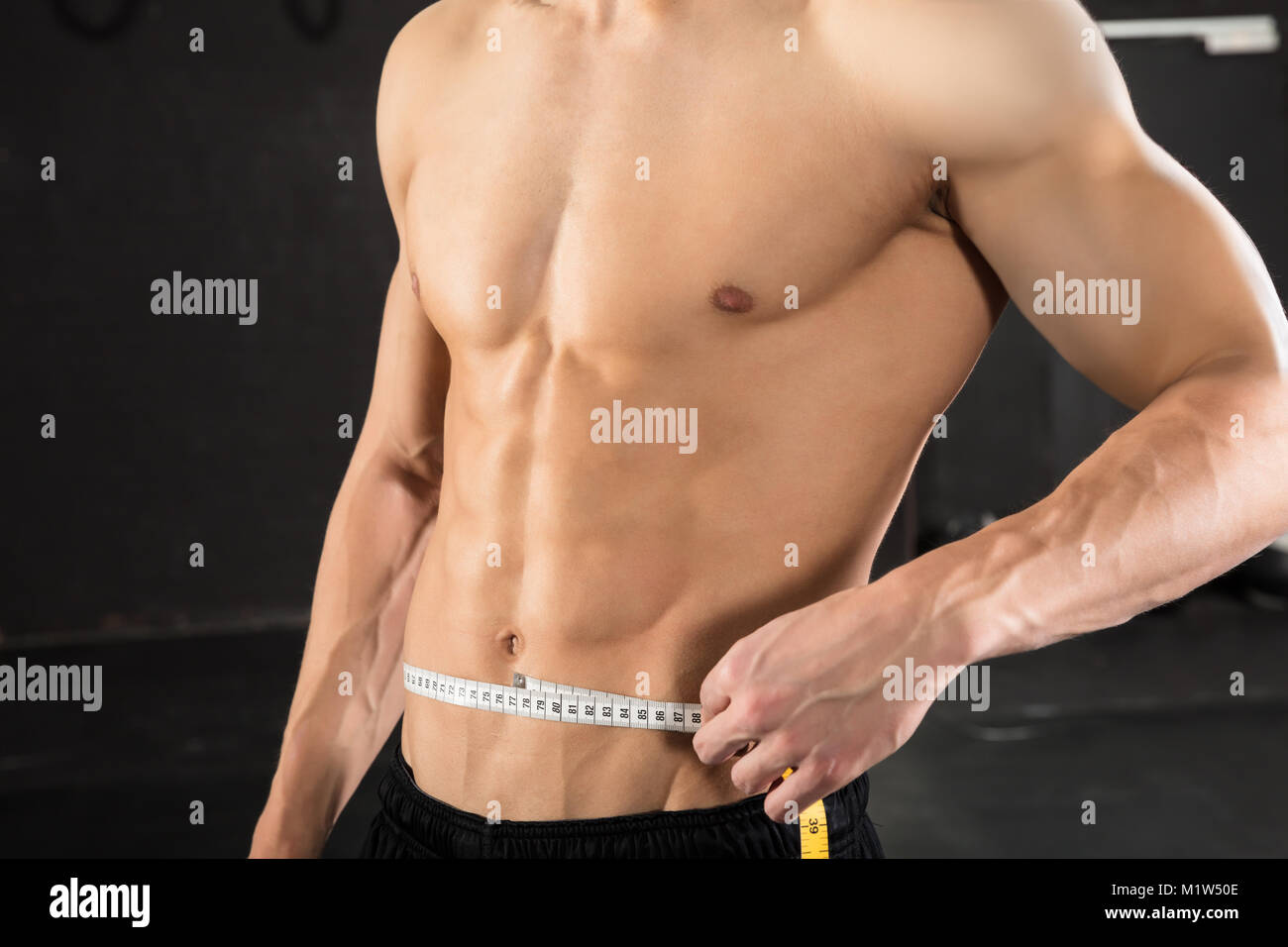 Image of muscular man measure his biceps with measuring tape in centimeters  Stock Photo - Alamy