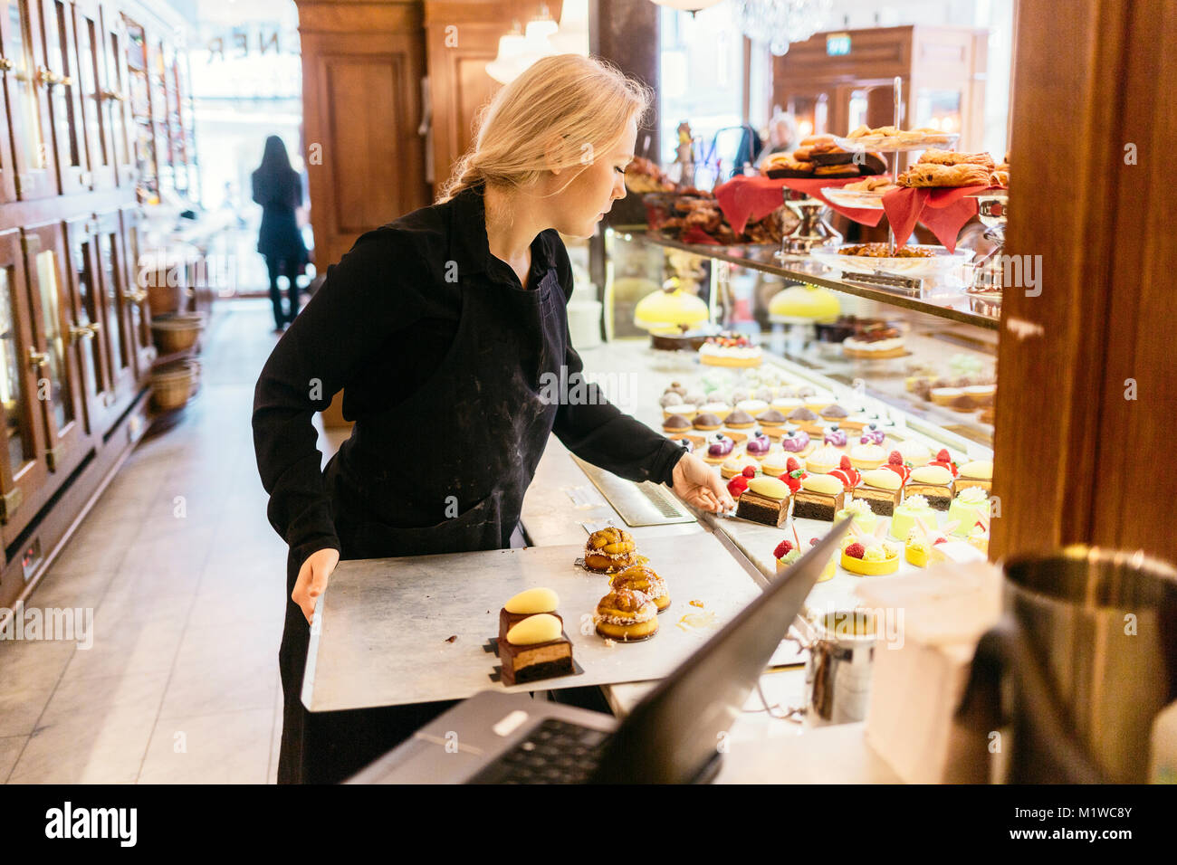 Baker putting baked goods in display window in Sweden Stock Photo