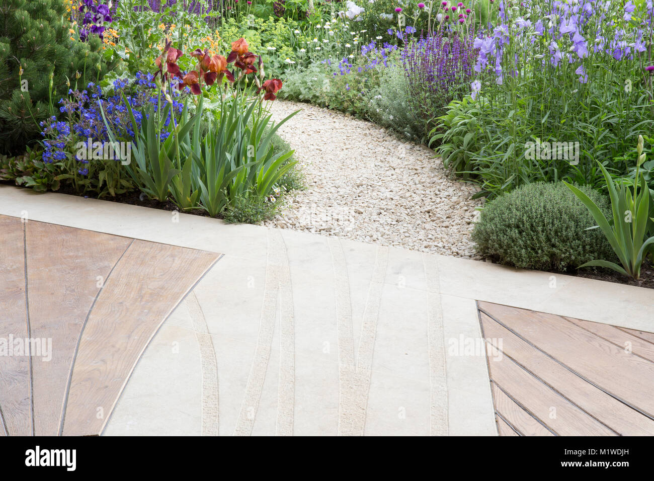Modern contemporary Wood wooden patio deck decking with Curved gravel garden path leading through a cottage wild garden, Chelsea Flower show UK Stock Photo