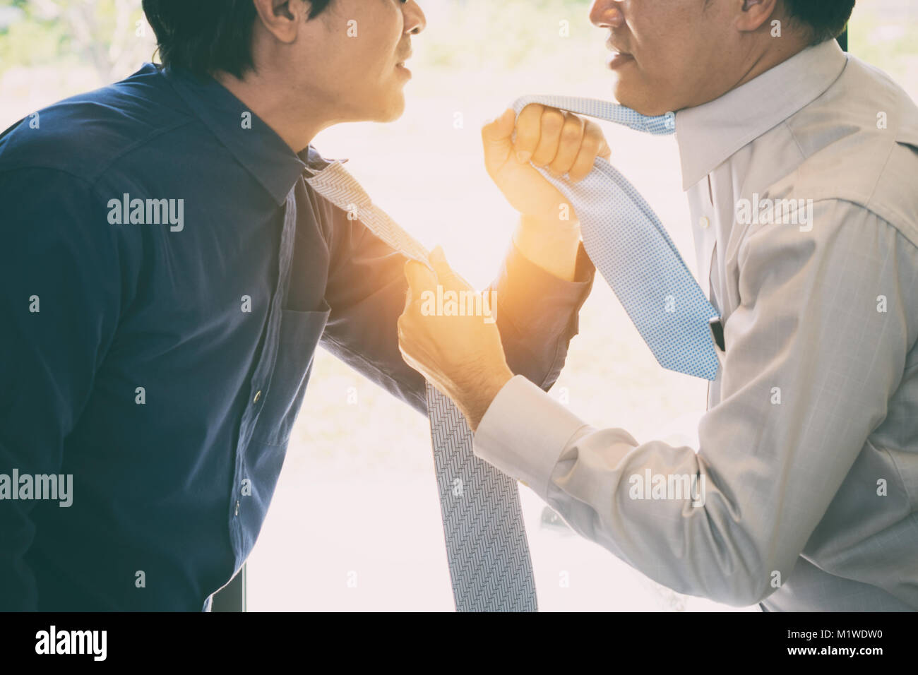 Asian businessman manager shouting to a stressed employee in office on meeting. Fighting businessmen tearing each other at their ties. Stock Photo