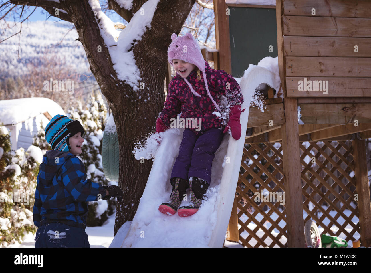 Siblings playing in snow covered playground Stock Photo - Alamy