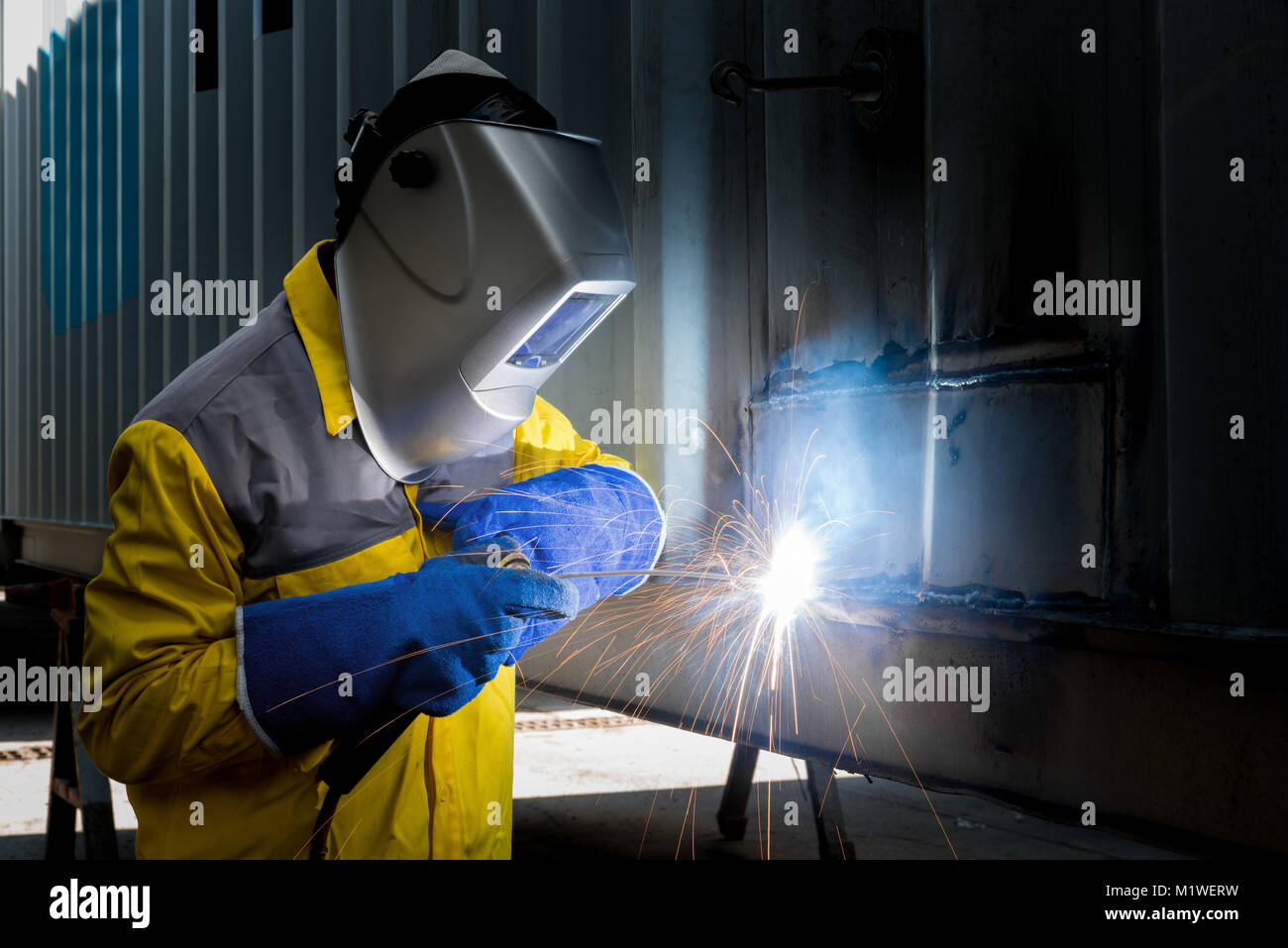 Industry worker with welding steel to repair container structures manufacture workshop. Container maintenance industry. Stock Photo