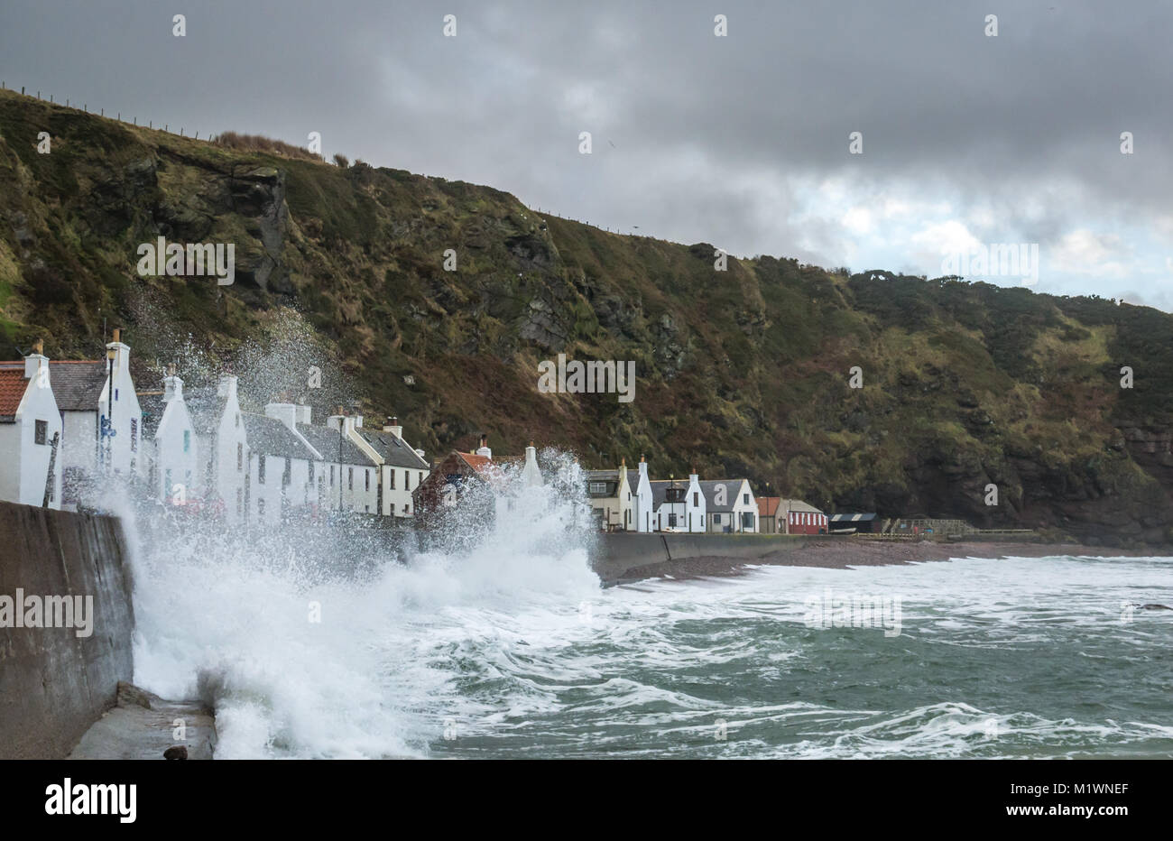 Pennan, Aberdeenshire, Scotland, United Kingdom, 2nd February 2018. The strong winds create a surge in the North Sea along the Northeast coast of Scotland, with large waves splashing against the promenade in the picturesque village, famous for being a film location for the movie Local Hero Stock Photo