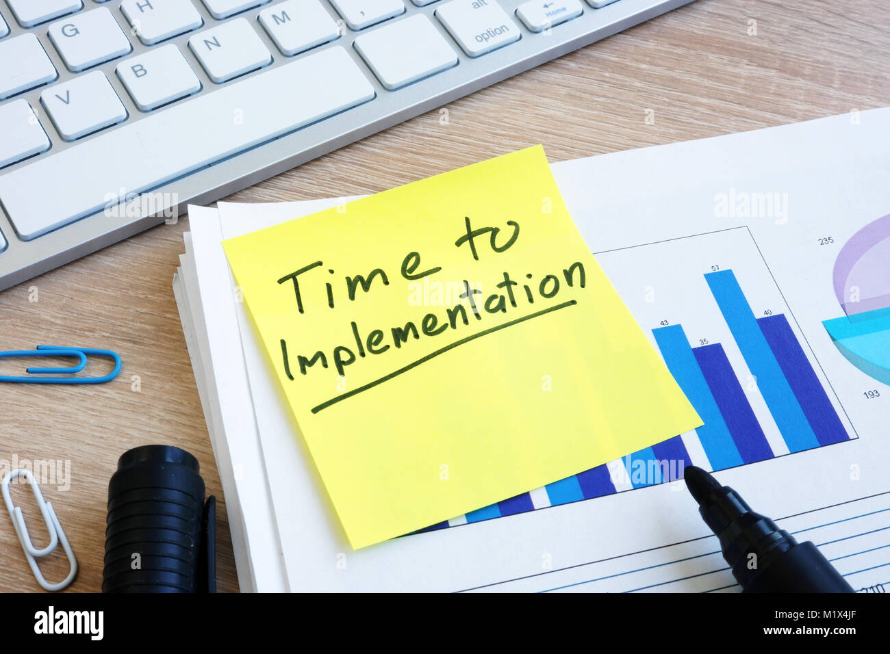 Memo stick with words Time To Implementation and documents. Stock Photo