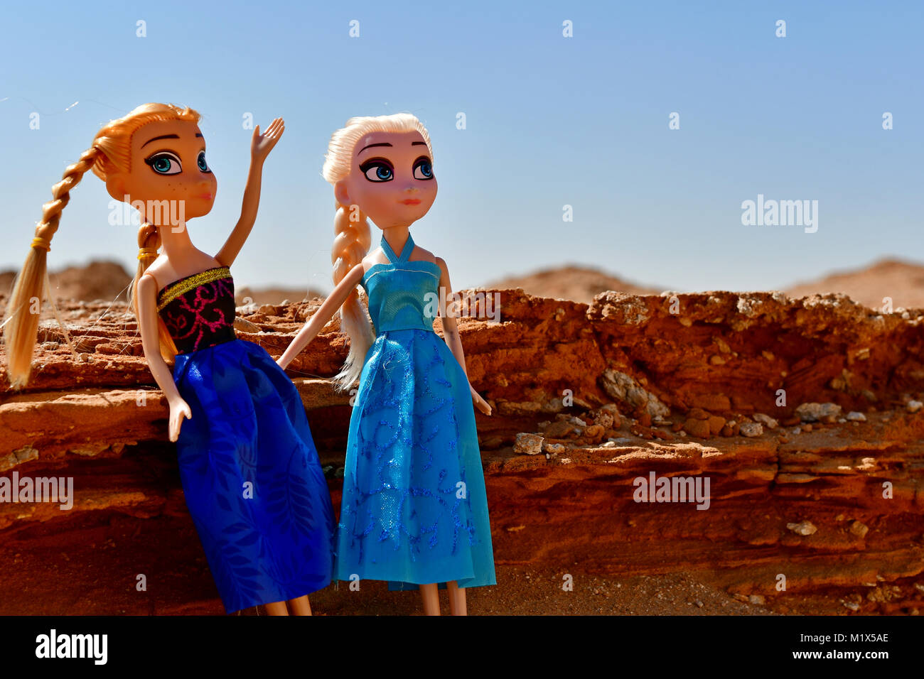 Barbie girls dressed in red and blue are posing for modeling photos in the desert rocks on location Stock Photo