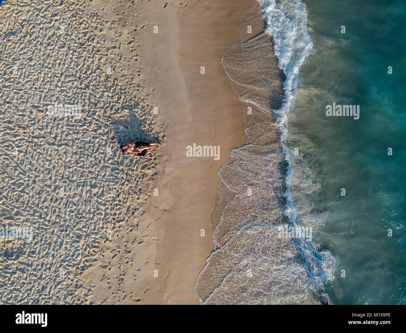 Drone photo of woman lying on the beach during sunset Stock Photo - Alamy