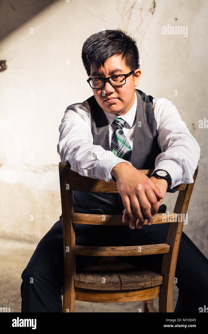 Young transgender man in formal clothing poses in a grungy urban location Stock Photo