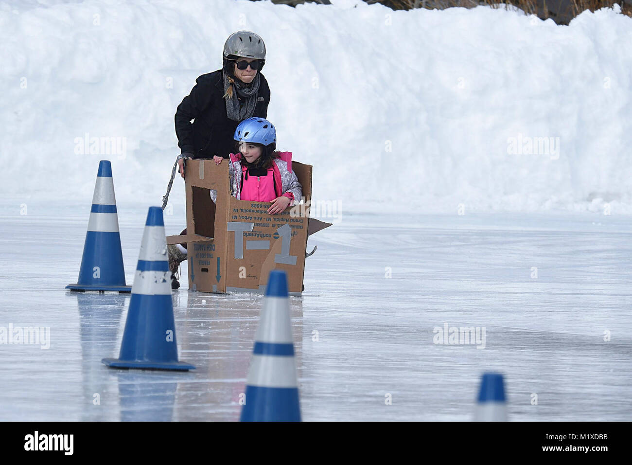 Jessica Pickett, Buckley Air Force Base spouse, and Anya Fournier, 9, slide in-between cones during the cardboard derby at the annual SnoFest at Copper Mountain, Colorado, Jan. 20, 2018. Participants had the option to bring their own cardboard creation or construct one with provided boxes for the event. (U.S. Air Force Stock Photo