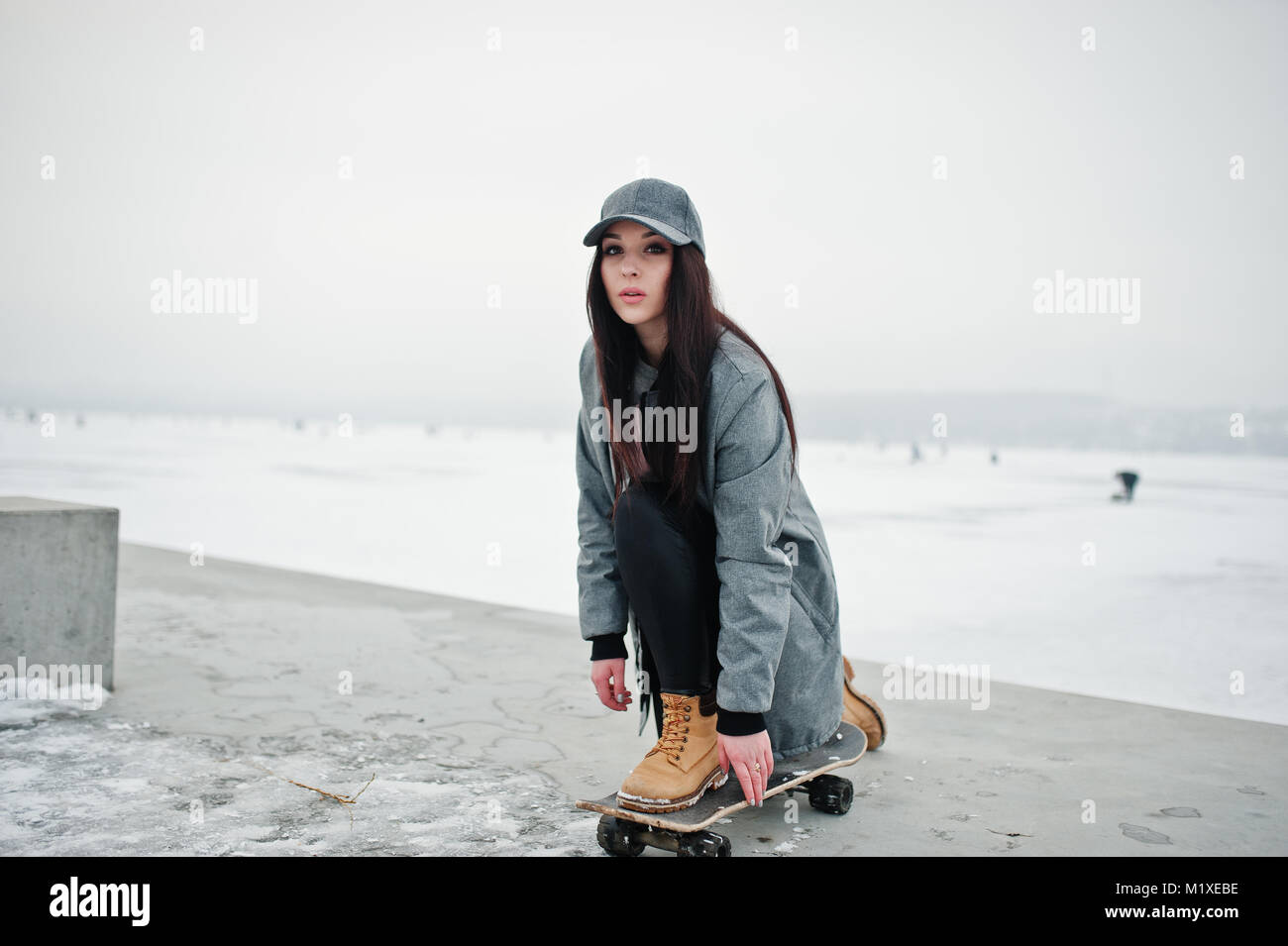 Stylish brunette girl in gray cap, casual street style with skate board on  winter day Stock Photo - Alamy