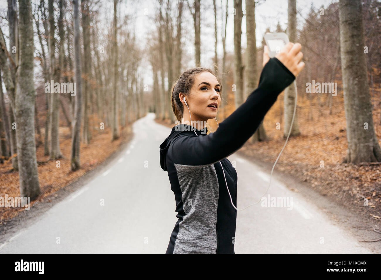 Young woman taking selfie on rural road in Sodermanland, Sweden Stock Photo