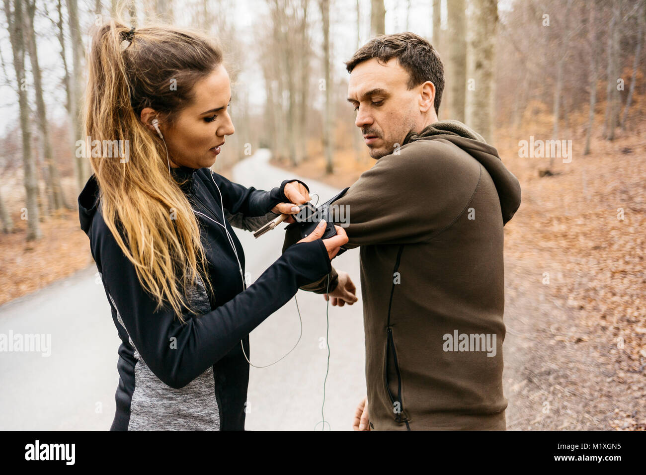 Young woman strapping man with smart phone holder in Sodermanland