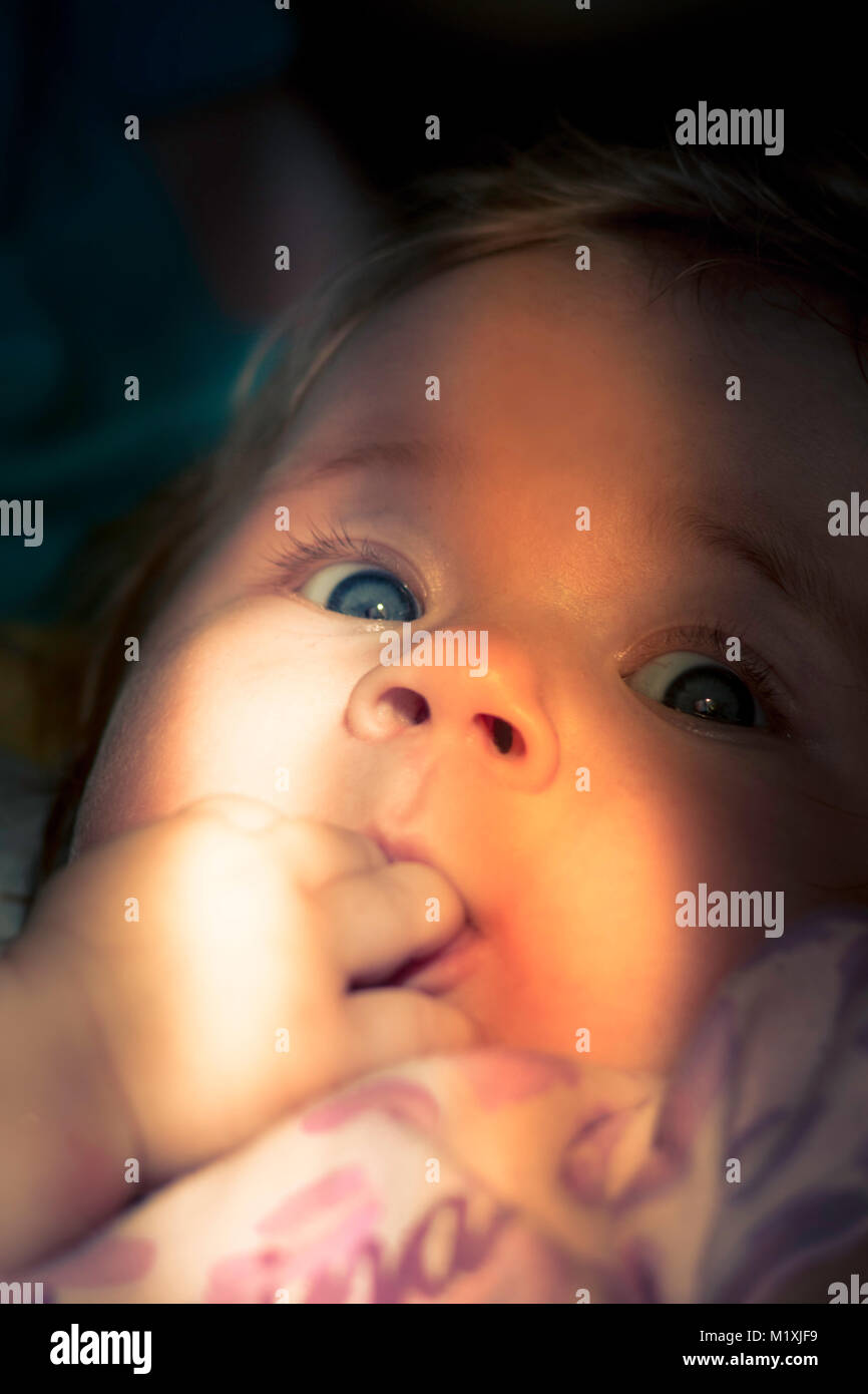 Curious look of a cute baby. Cute looking child. A sunlight on the child's face. Newborn. A curious look of a little girl. Children's portrait. girl Stock Photo