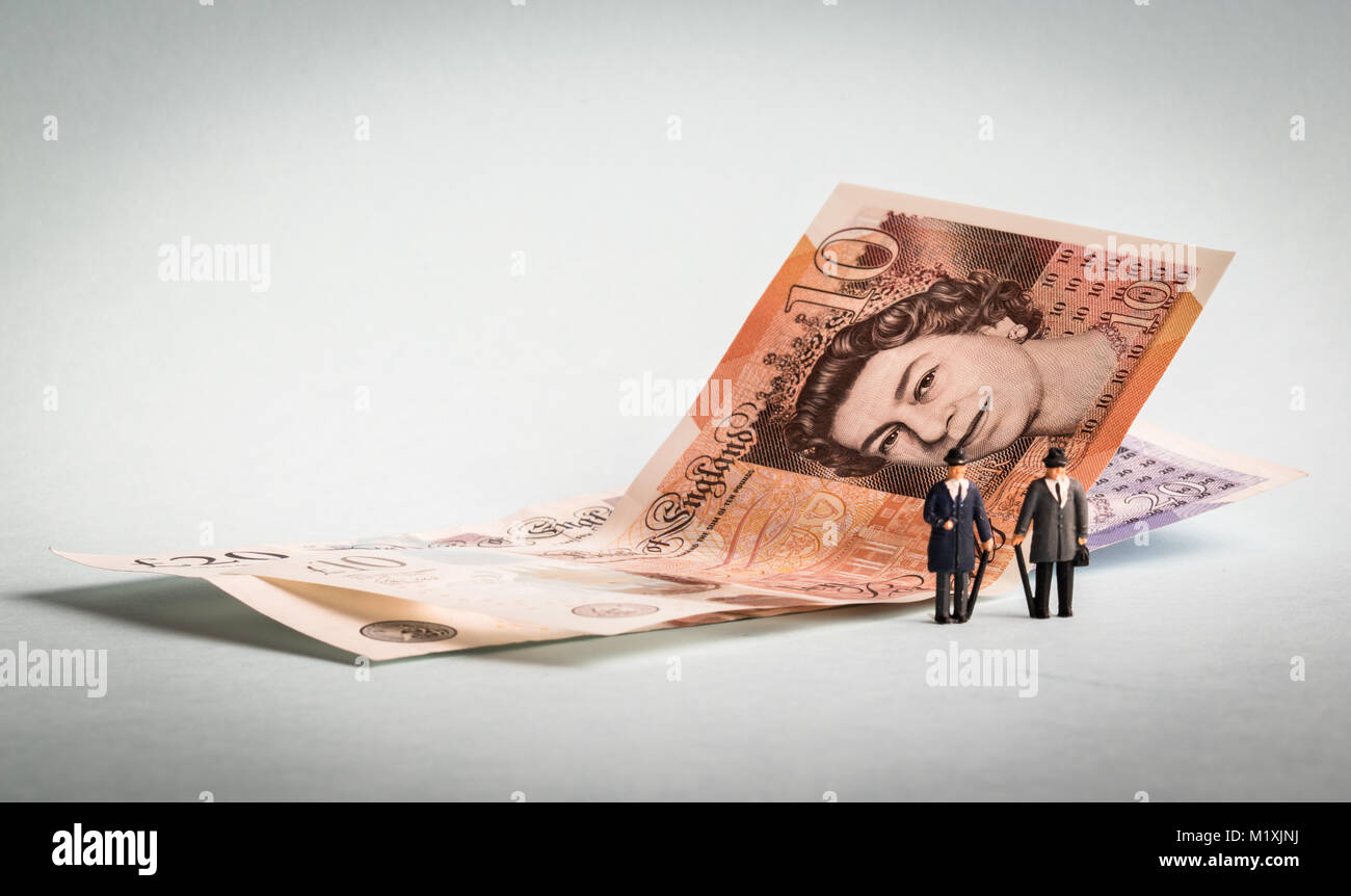 Miniature business figures standing by cash notes currency Stock Photo