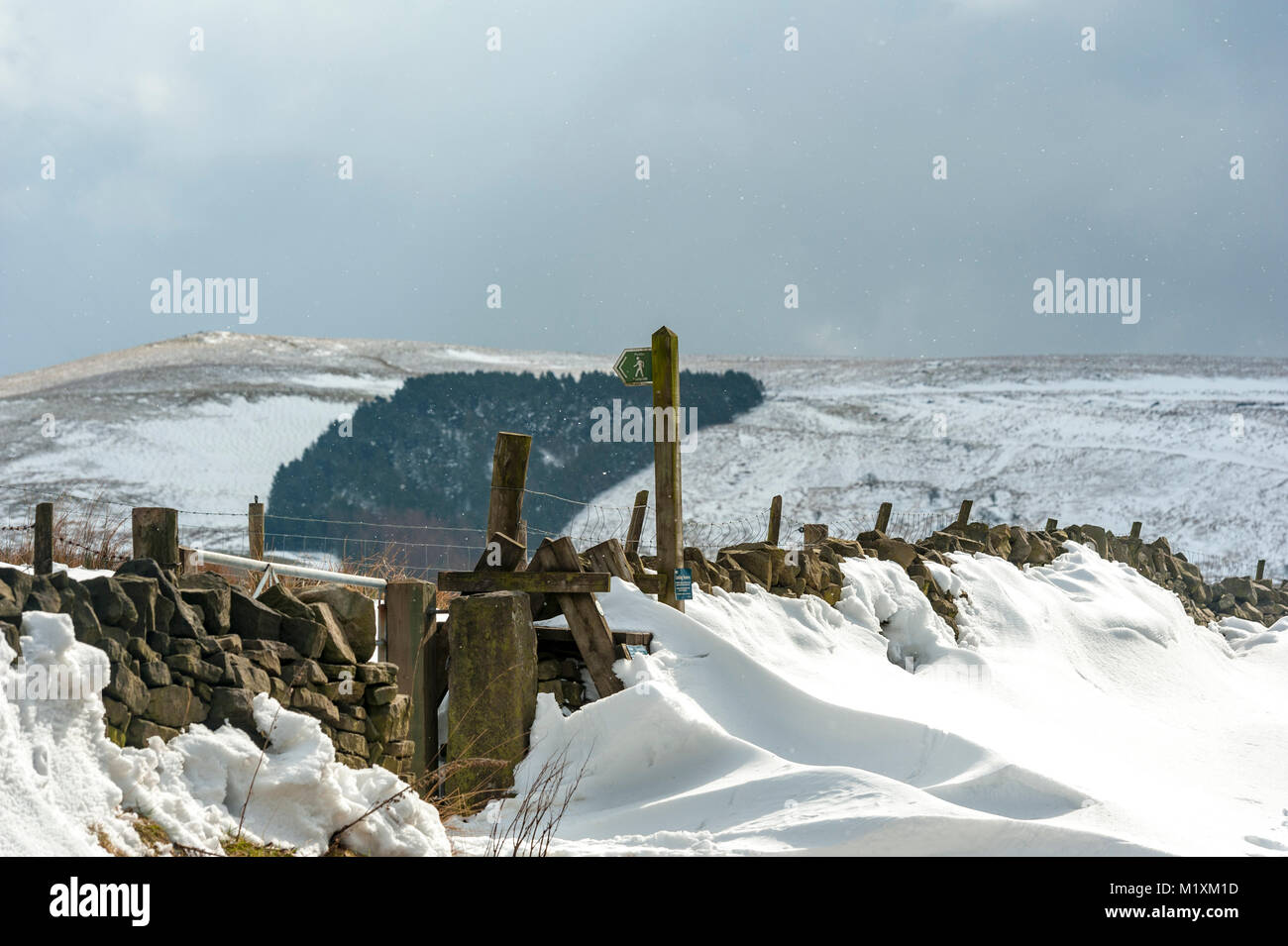 Walking in the snow pointing the way with a sign marker Lancashire moorland Stock Photo