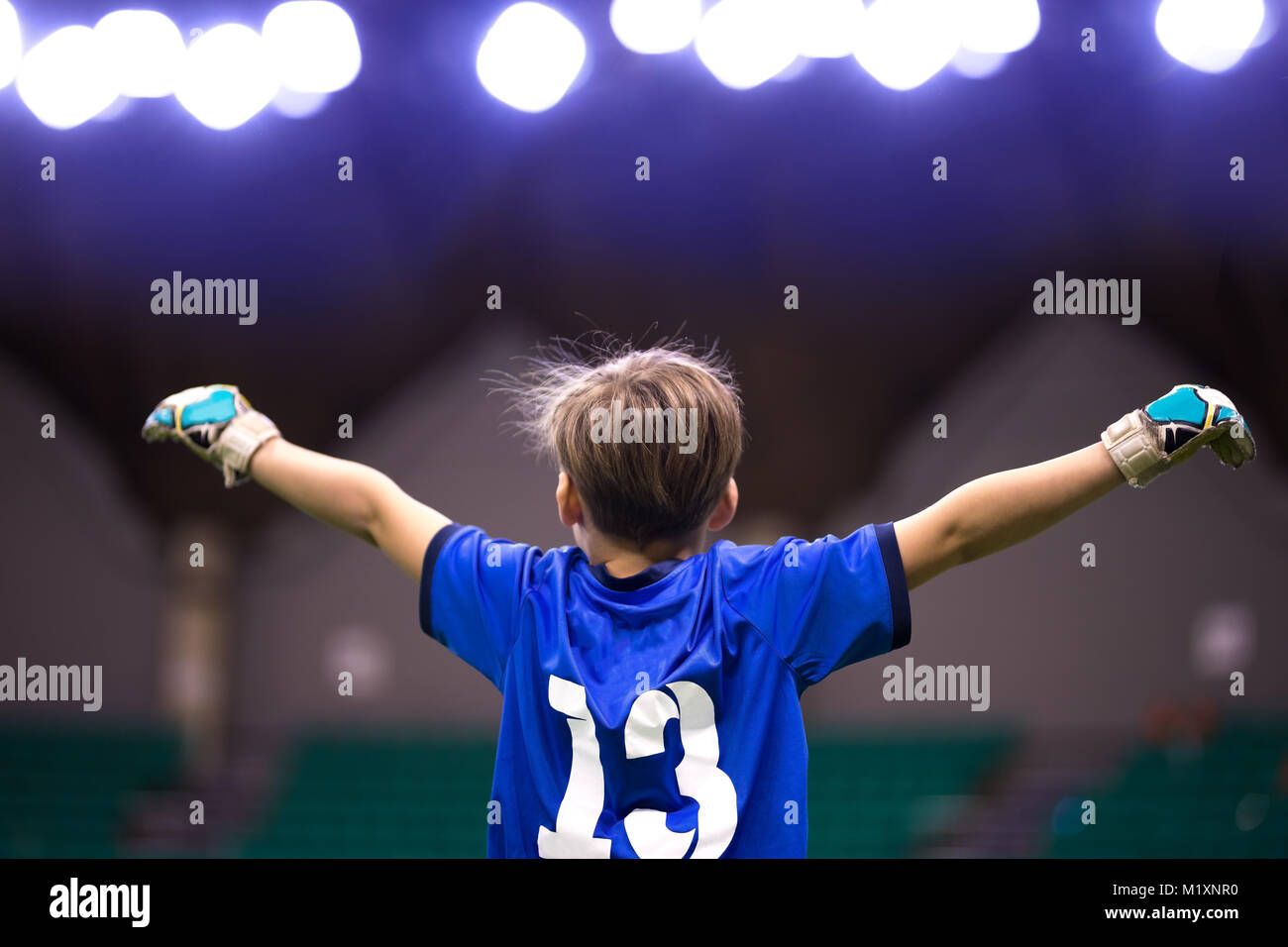 Boy sport soccer player celebrating the victory. Child winner. Cheering kid after score the goal. Football futsal indoor tournament for school kids Stock Photo