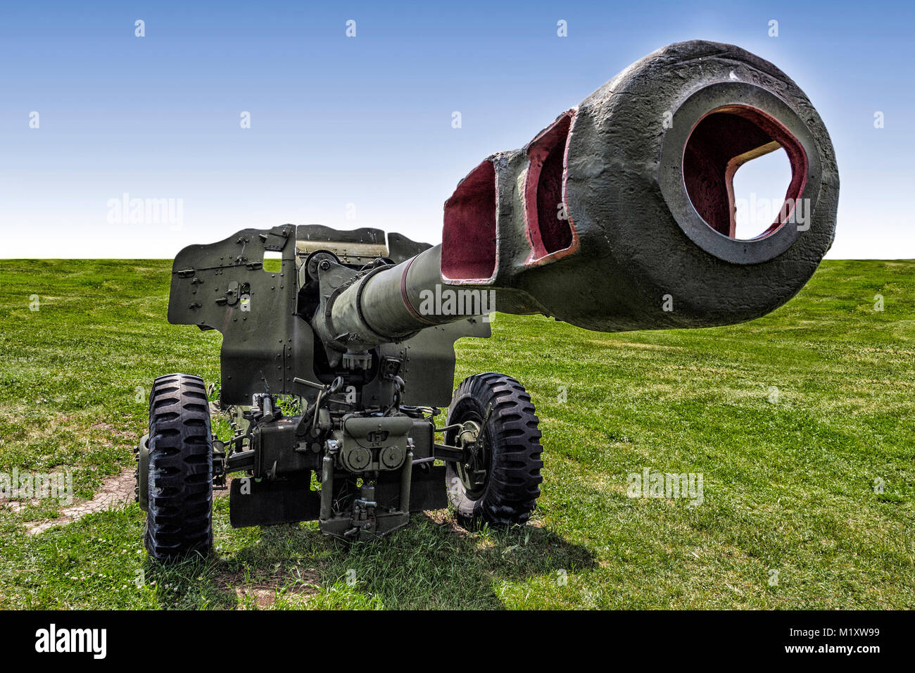 The old artillery cannon stands in the open field on the green grass. Stock Photo