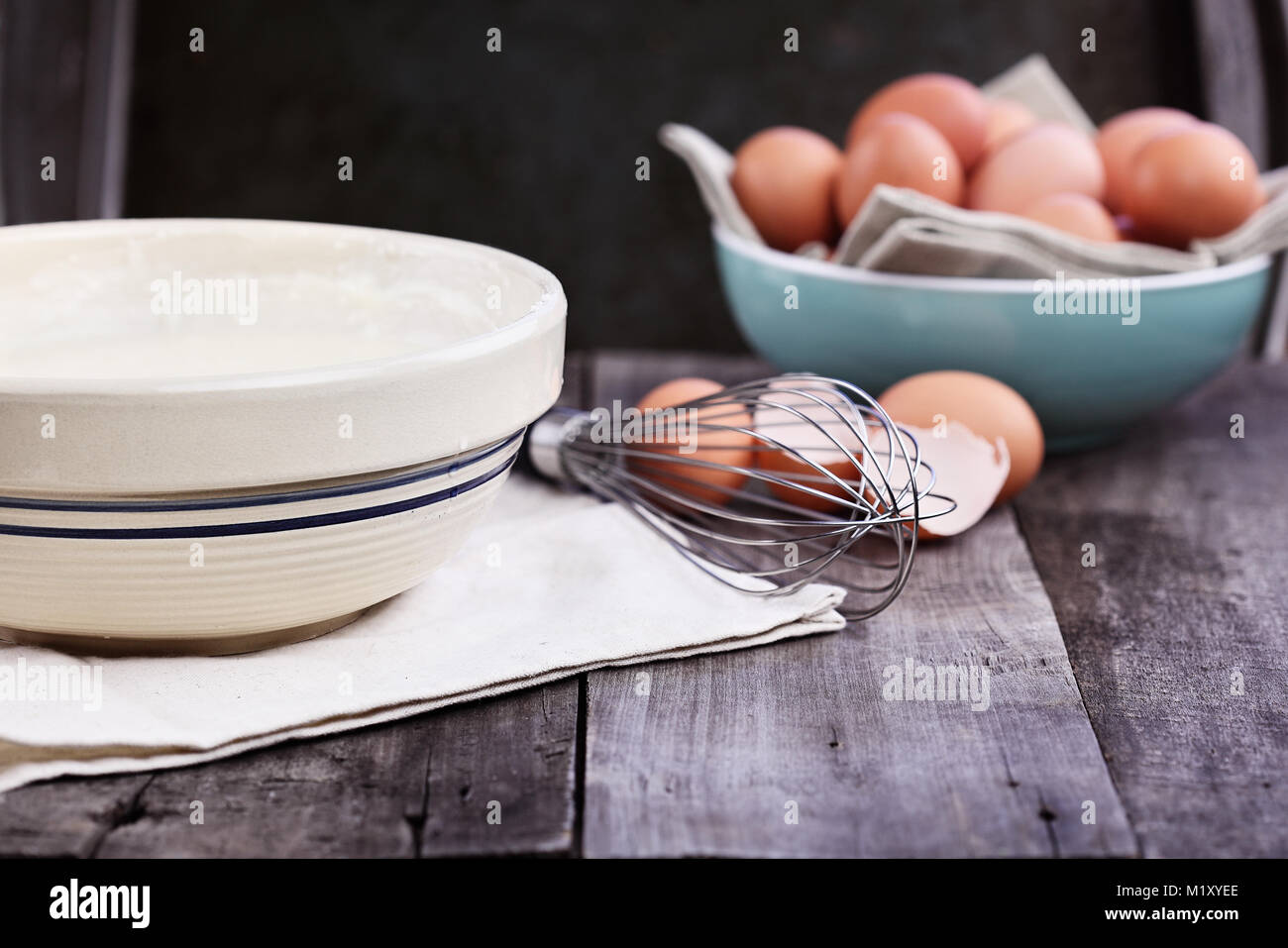 Bowl of homemade pancake batter mix with farm fresh brown eggs in background. Extreme shallow depth of field. Perfect for Shrove Tuesday. Stock Photo