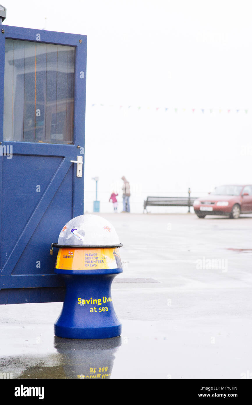 RNLI charity donation box used to prop open the door of the harbour masters hut on the Prince of Wales Pier, Falmouth, Cornwall. Stock Photo