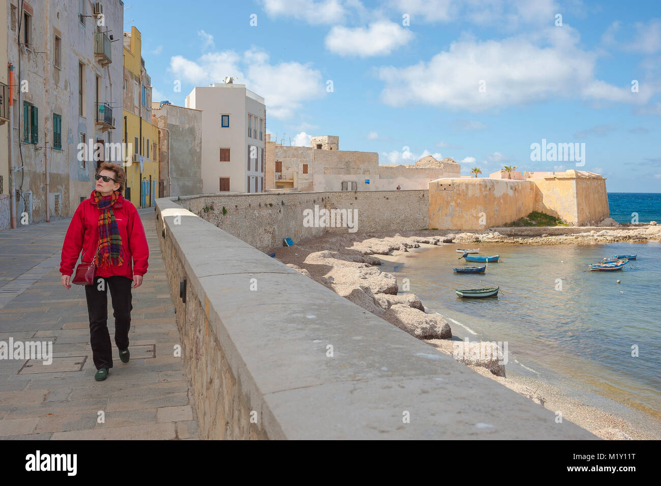 Trapani Sicily sea wall, view of a single mature woman walking along the  sea wall in Trapani harbor, Sicily (MODEL RELEASED Stock Photo - Alamy