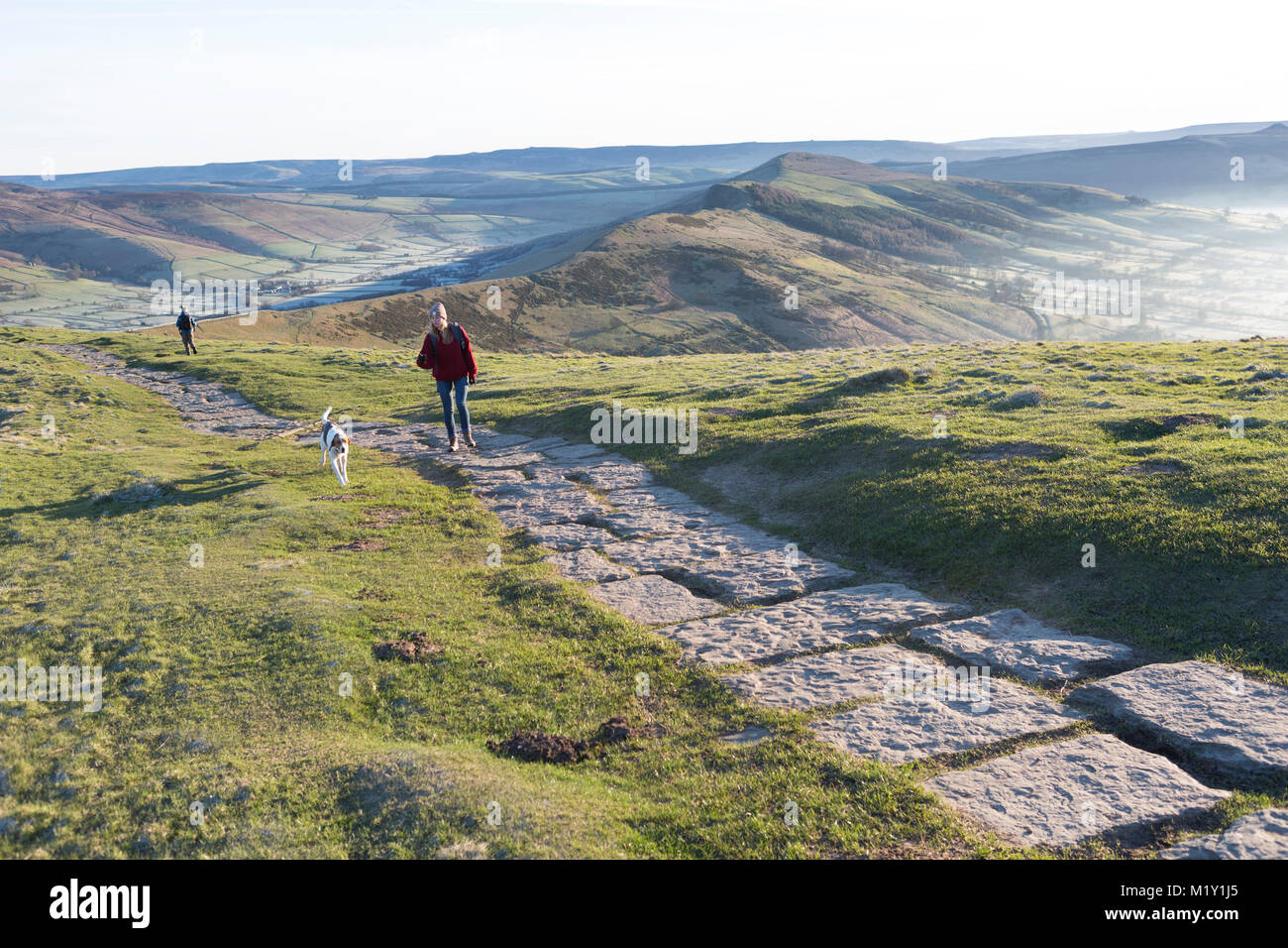 UK, Derbyshire, a walker and her dog on the Mam Tor ridge pathway. Stock Photo
