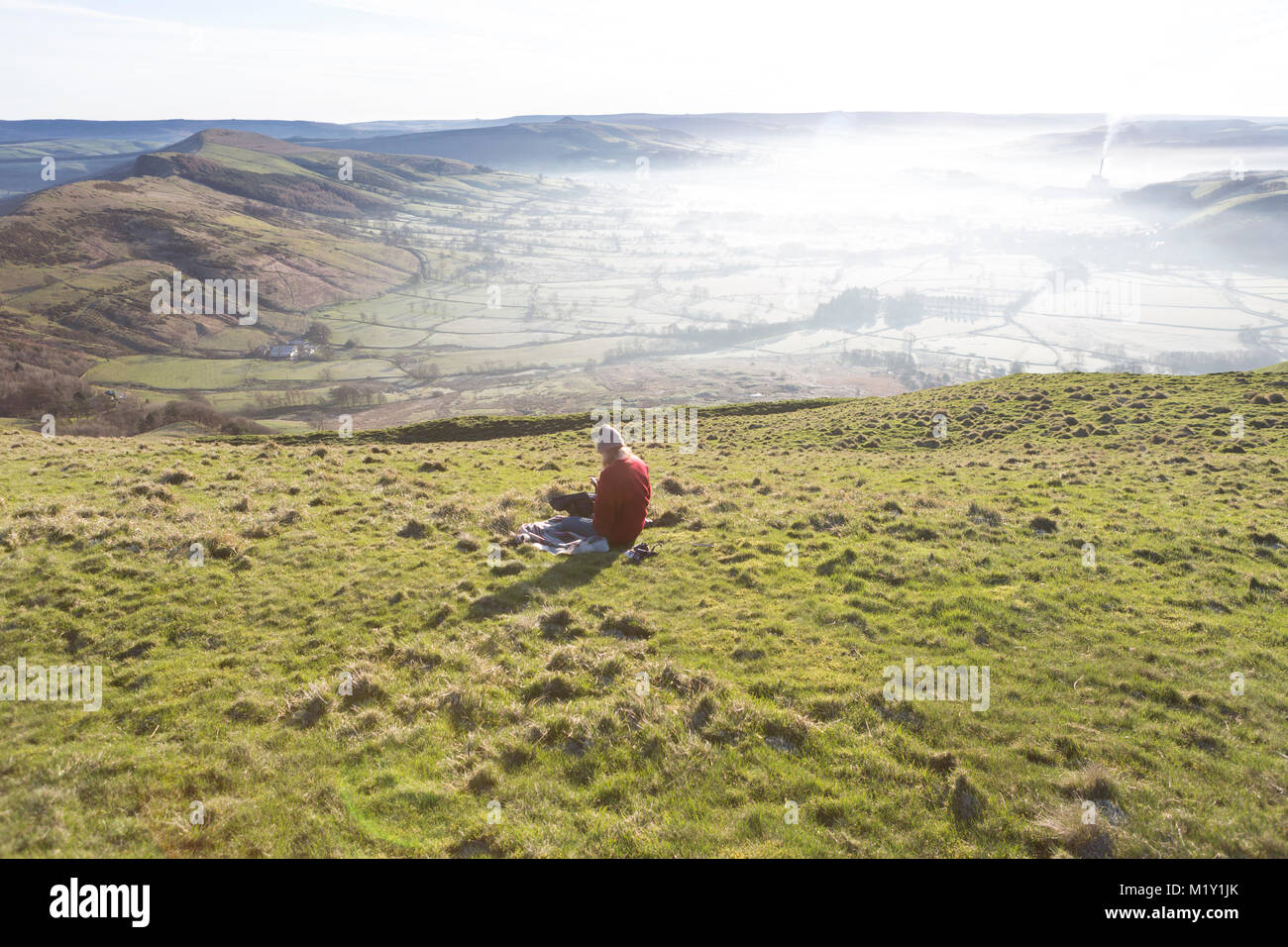 UK, Derbyshire, a walker taking a rest  on Mam Tor overlooking Hope Valley. Stock Photo