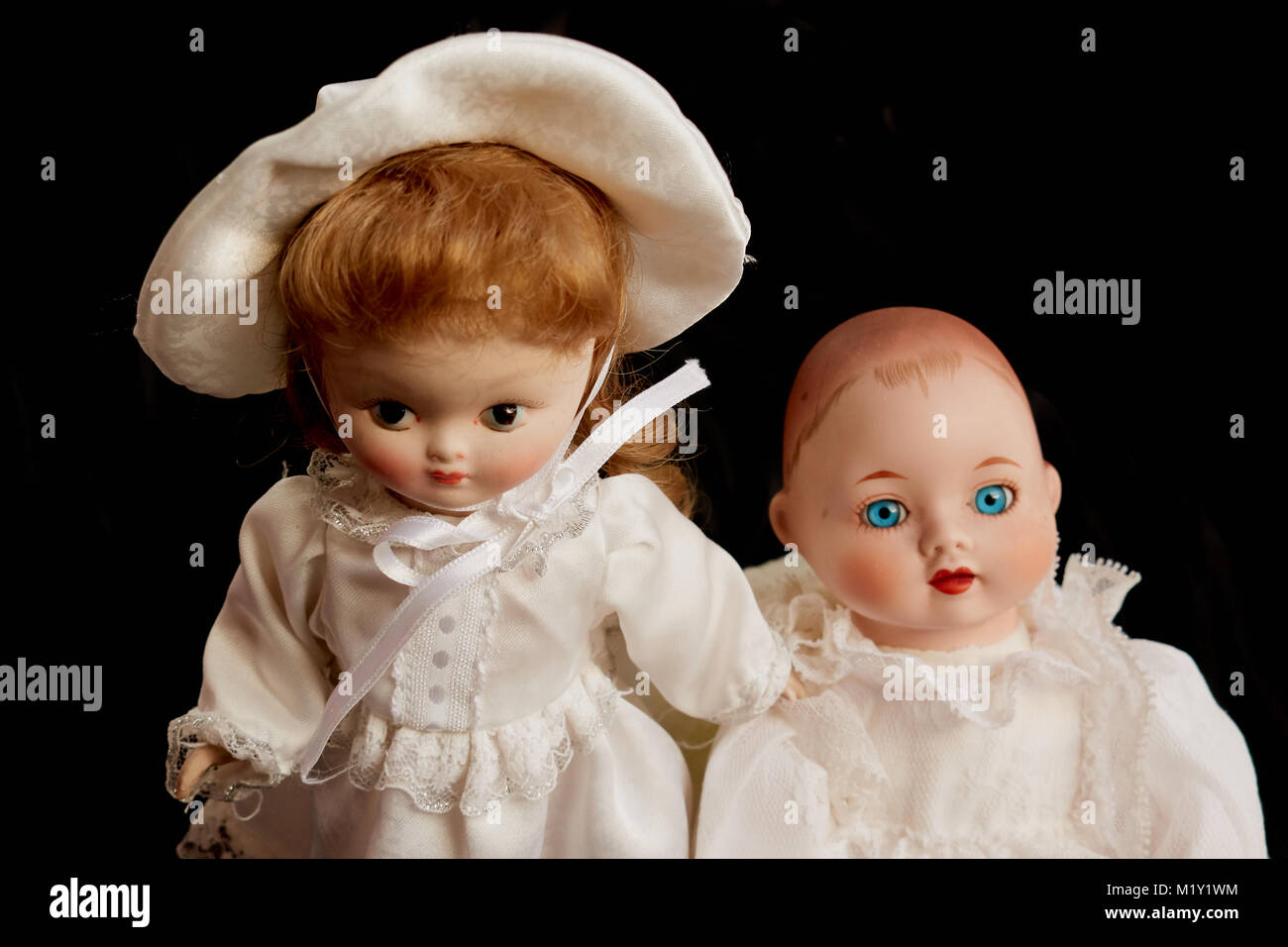 Closeup of two old porcelain dolls on black background Stock Photo