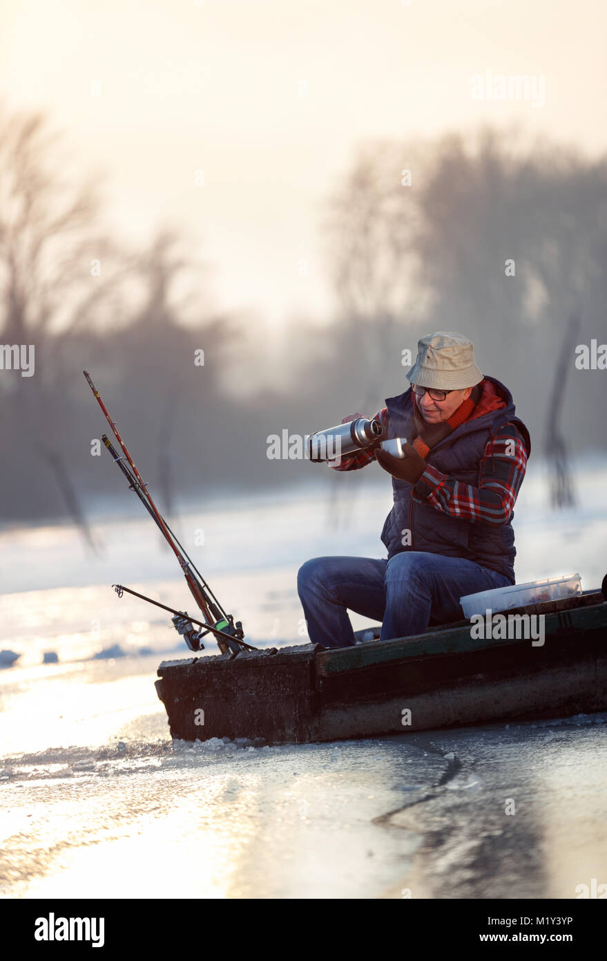Man ice fishing on a frozen lake. Devils lake in North Dakota in the winter  at sunset Stock Photo - Alamy