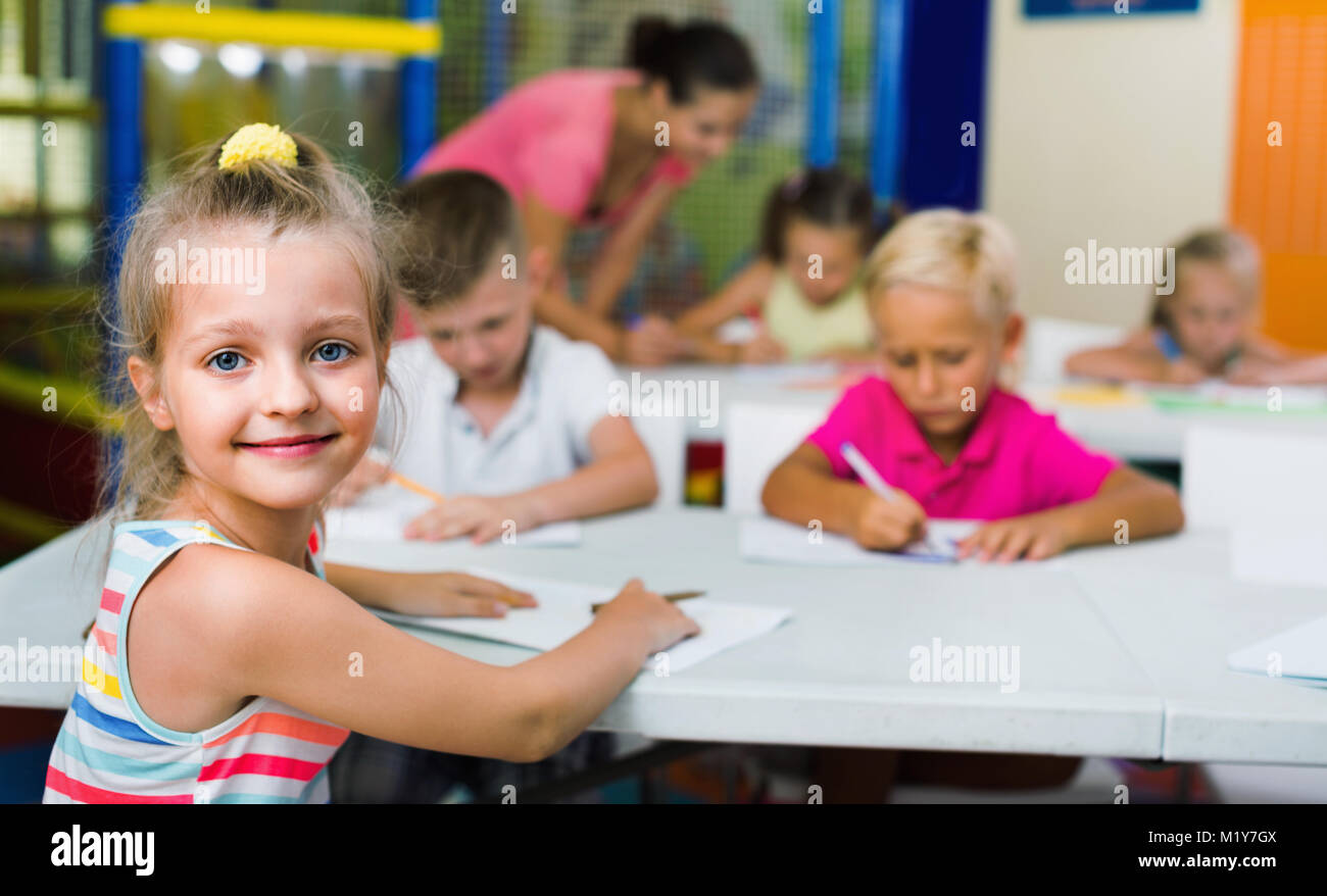 Portrait of cheerful smiling diligent pupil girl studying in school ...