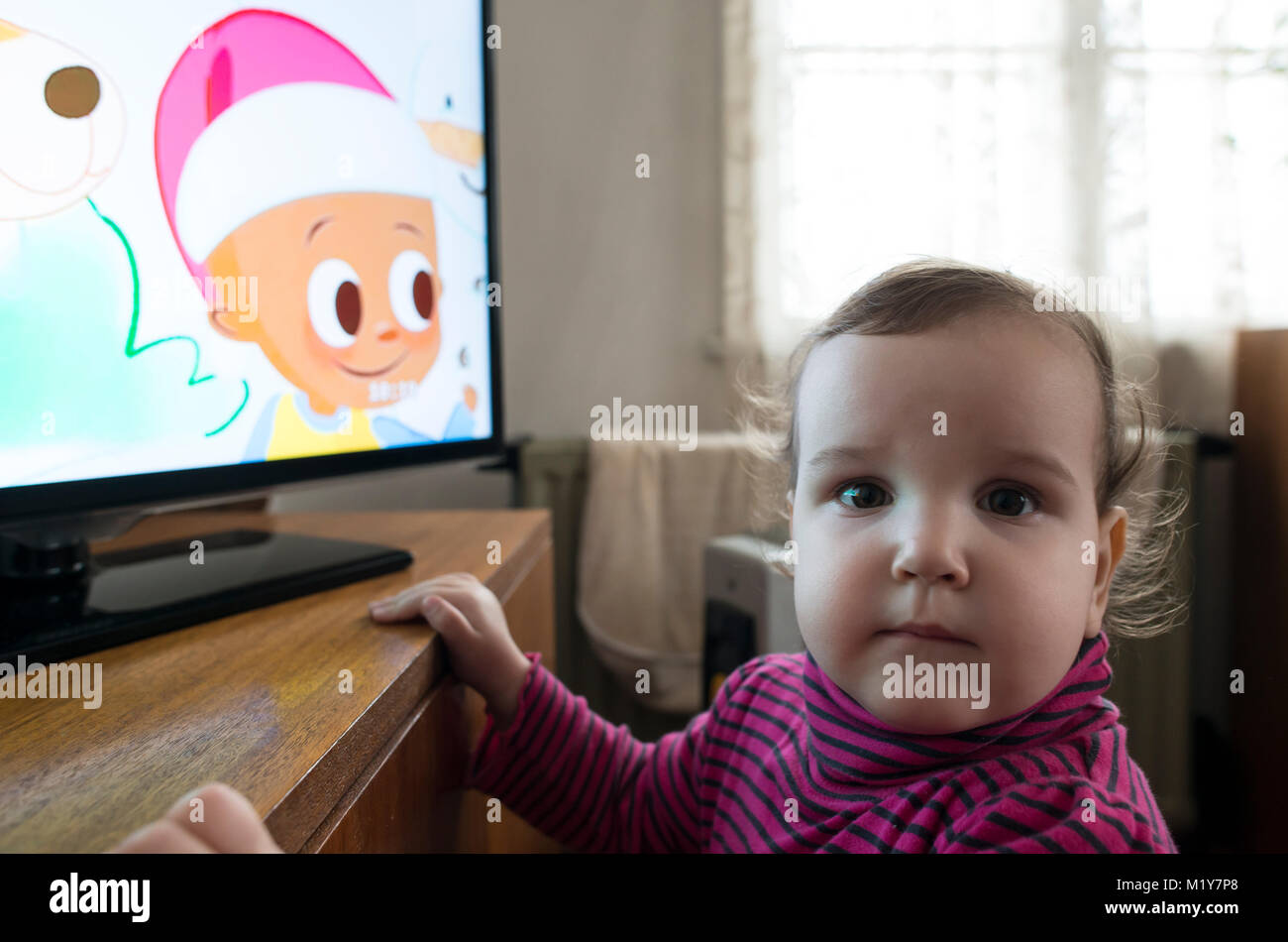 Baby girl watch TV. In fron of the TV Stock Photo Alamy