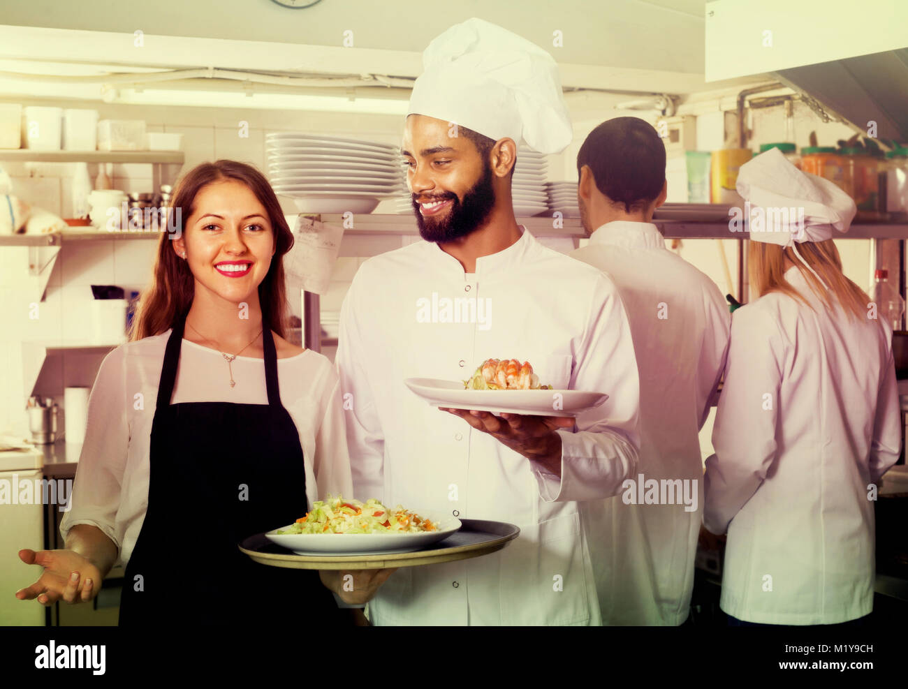 spanish waitress and crew of professional cooks posing at restaurant