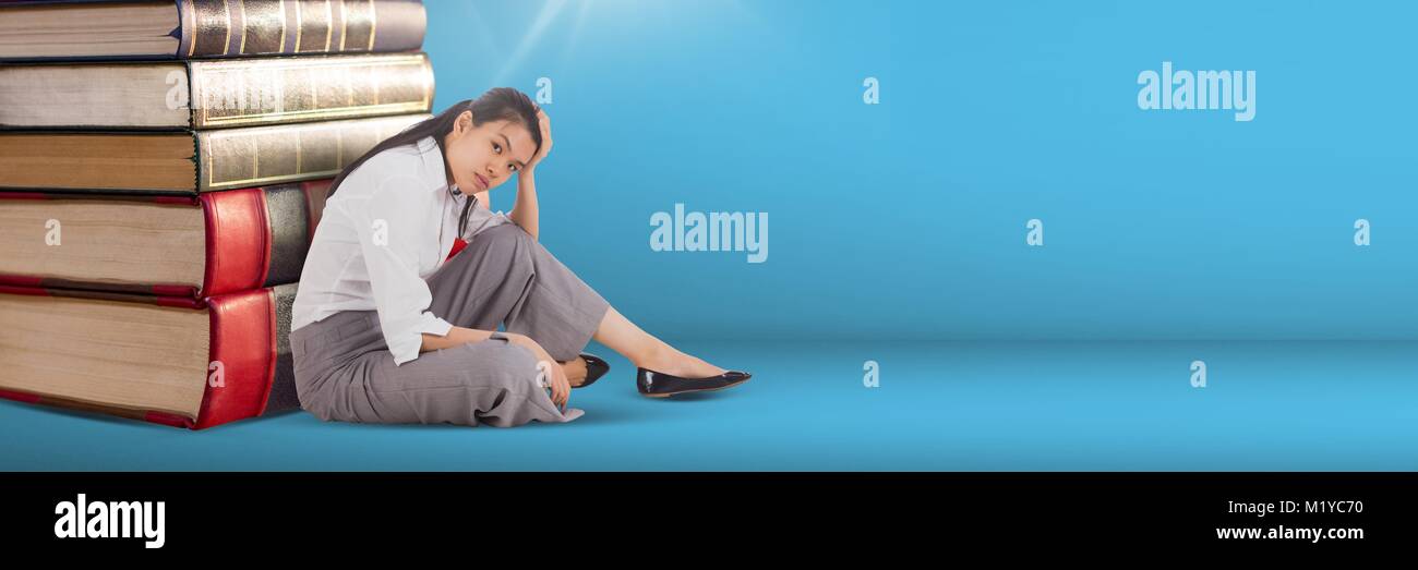Business woman sitting next to a pile of books on blue background Stock ...