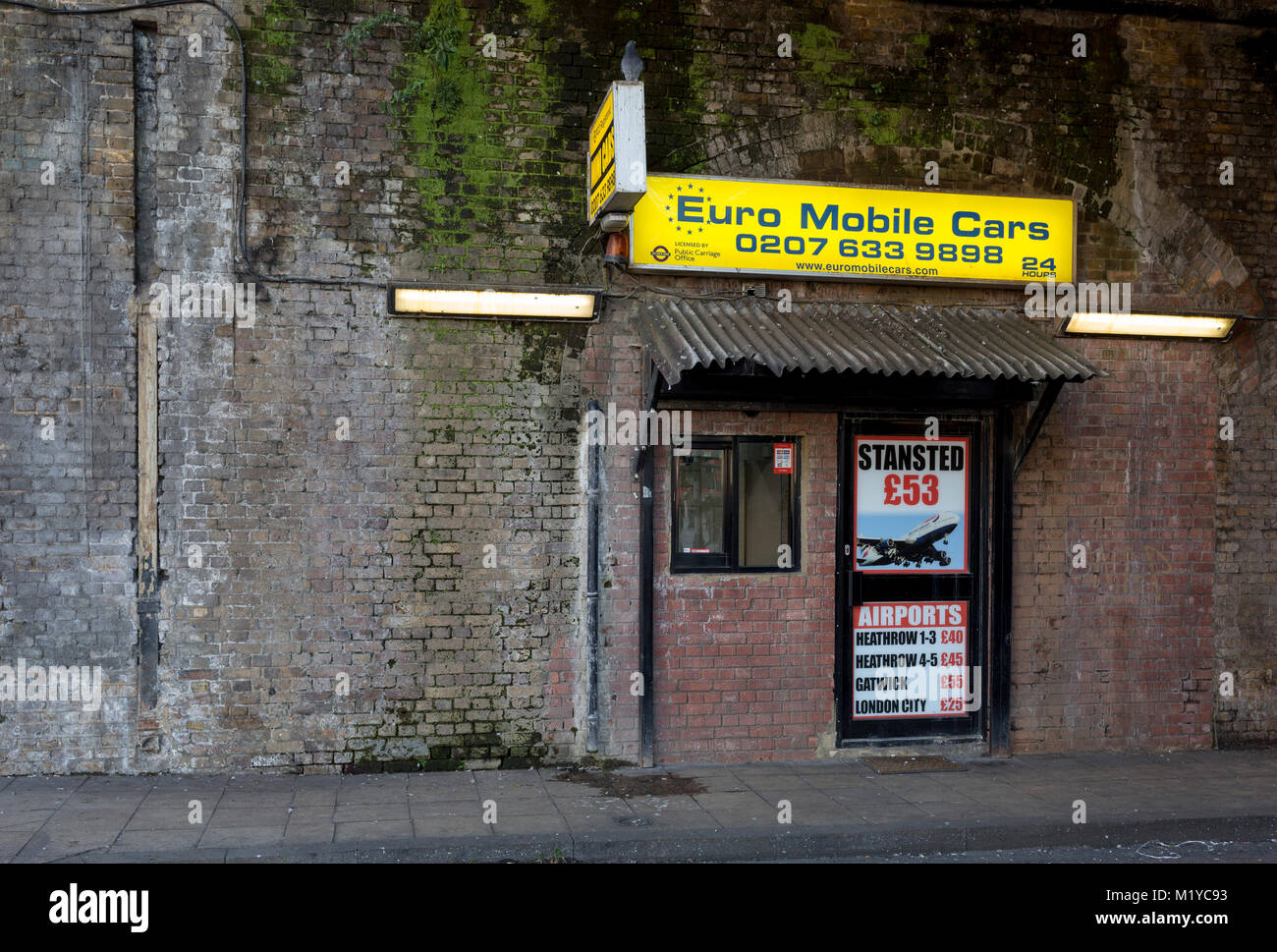 A taxi cab office advertising airport run fairs beneath a Victorian bridge near Waterloo station, on 30th January 2018, in the south London borough of Southwark, England. Stock Photo